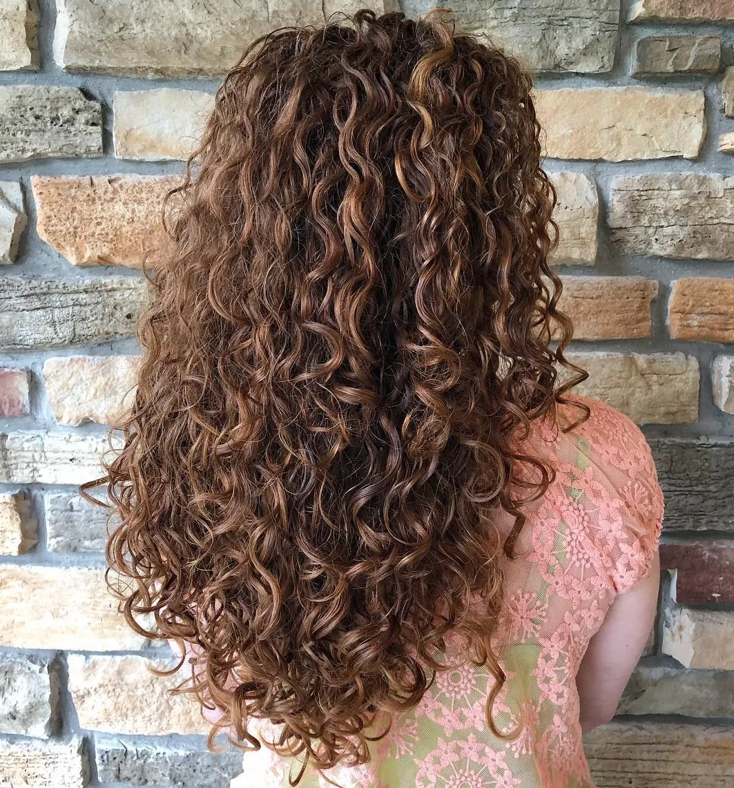 Femme avec une coupe en V sur cheveux longs mi-dos, coiffure lisse et définie avec finition anti-frisottis.







