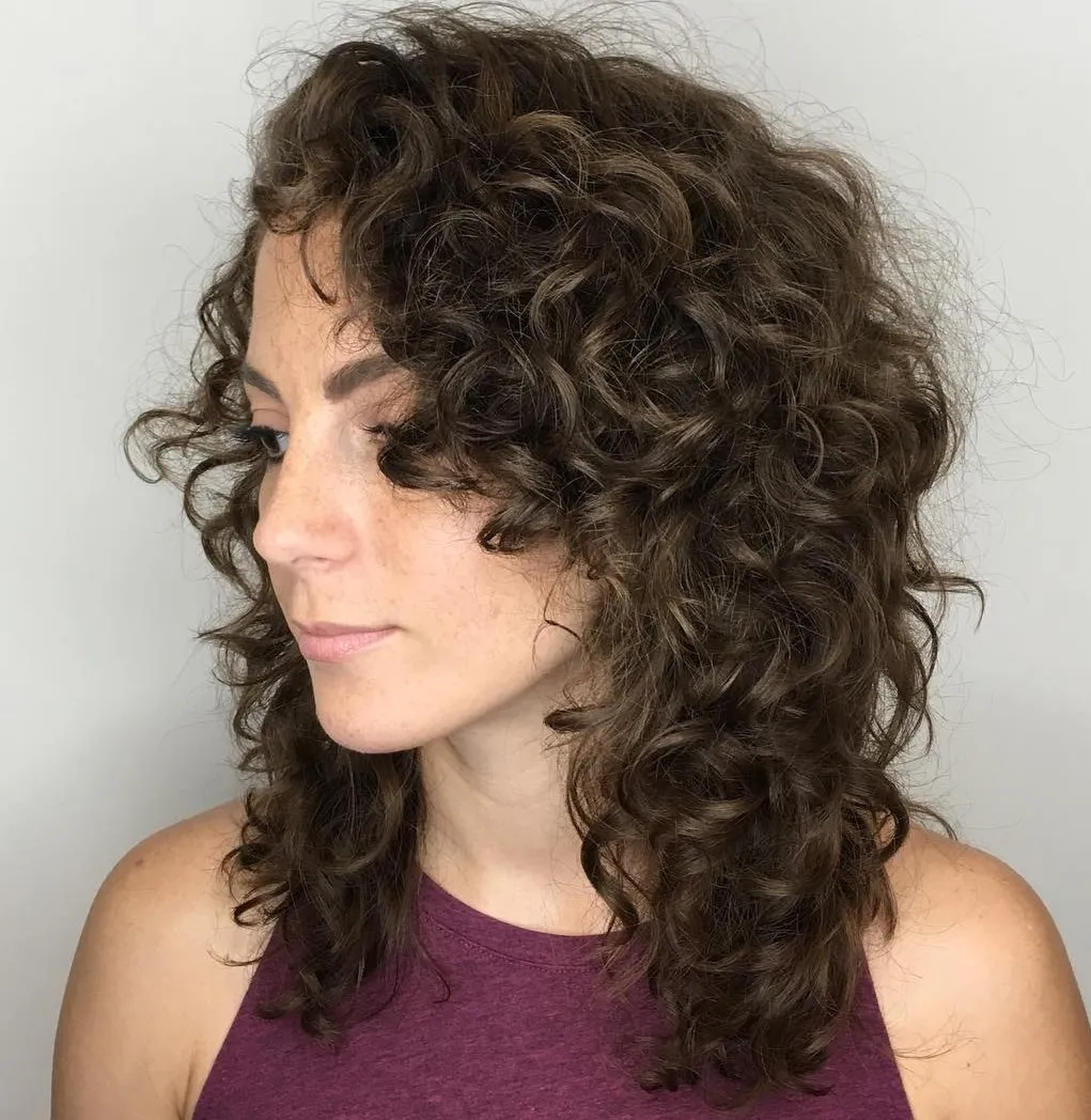 Femme avec une coupe mi-longue dégradée, cheveux ondulés au volume naturel et look moderne