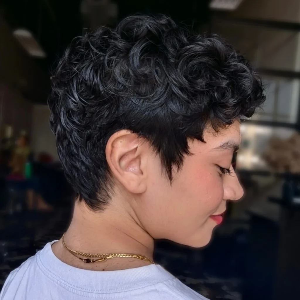Femme avec une pixie bouclée courte tendance, coupe stylée et volumineuse adaptée aux boucles serrées ou souples.